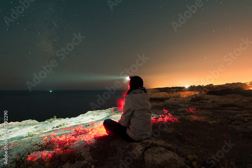 Sitting woman with head flashlight during starry night photo