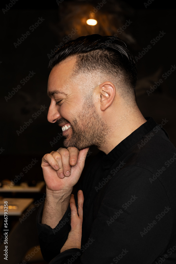 Cheerful chef touching chin and closing eyes Cheerful chef touching chin and closing eyes