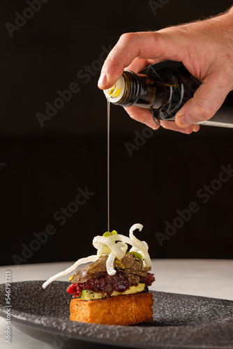 Crop cook pouring oil on deer tartar brioche