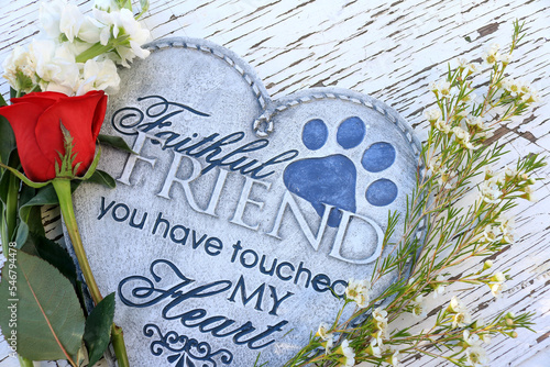Flowers and a red rose surrounding a heart shaped plaque.