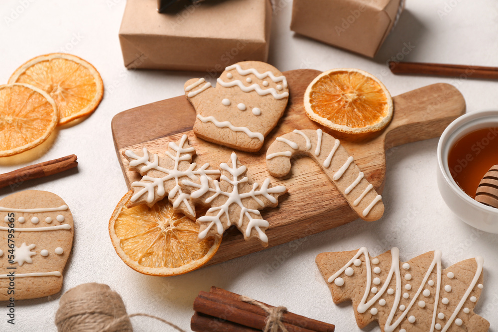 Wooden board with tasty Christmas cookies and orange slices on light background Wooden board with tasty Christmas cookies and orange slices on light background