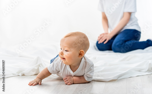a child in a white t-shirt and blue jeans crawls on the floor. family in studio or at home