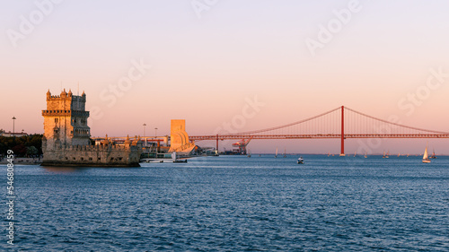 Panorama of Belém in Lisbon, the capital of Portugal. Sunset over Tagus river. Cityscape with Torre de Belém, Belém Tower and red iconic 25 de Abril Bridge, 25th of April Bridge.