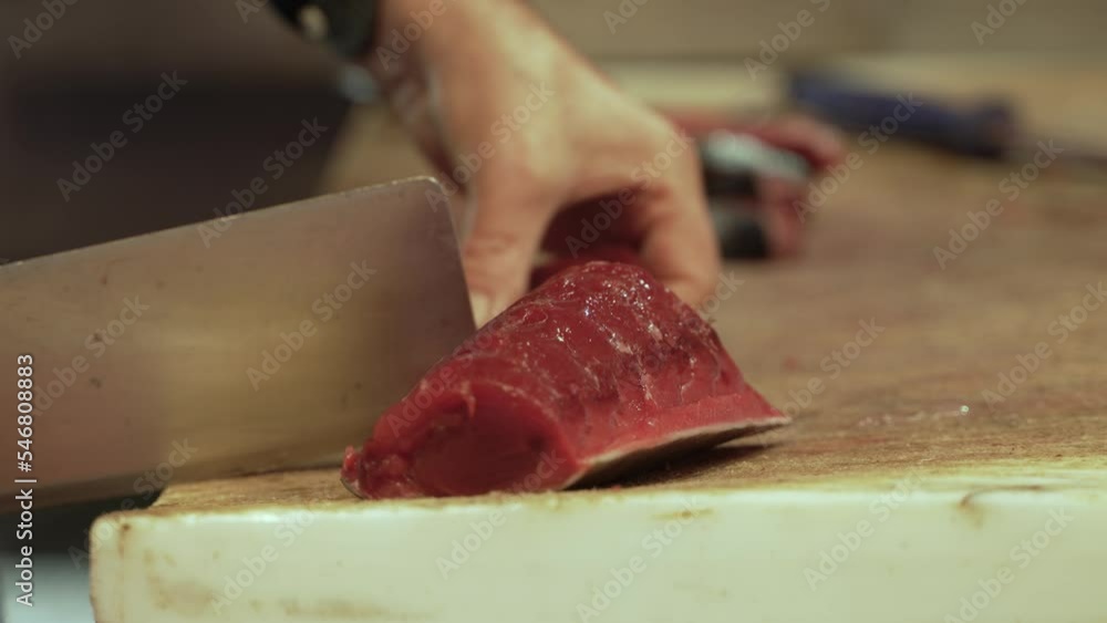 Close-up of hands cutting tuna fish at the local fish market. Male hands slicing tuna fillet on the counter with a knife Close-up of hands cutting tuna fish at the local fish market. Male hands slicing tuna fillet on the counter with a knife