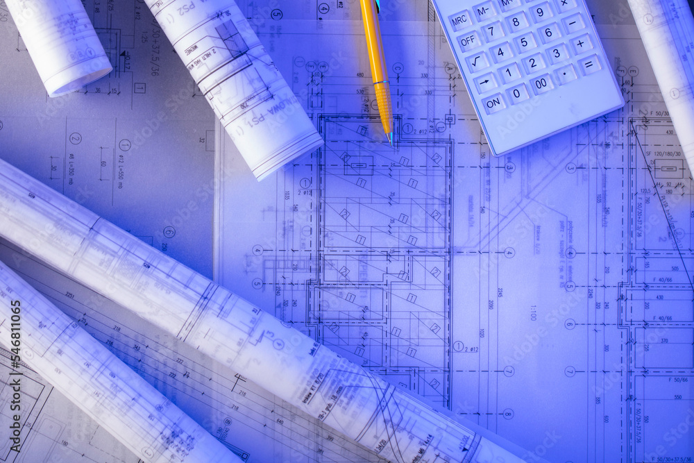 Contractor theme. Plans, notebook and tool kit of the contractor: yellow hardhat, libella, saw and yardstick on the table. Contractor theme. Plans, notebook and tool kit of the contractor: yellow hardhat, libella, saw and yardstick on the table.