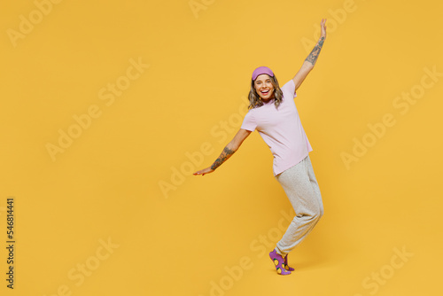 Full body young fun woman she wears purple pyjamas jam sleep eye mask rest relax at home dance with outstretched hands stand on toes leaning back isolated on plain yellow background Night nap concept © ViDi Studio