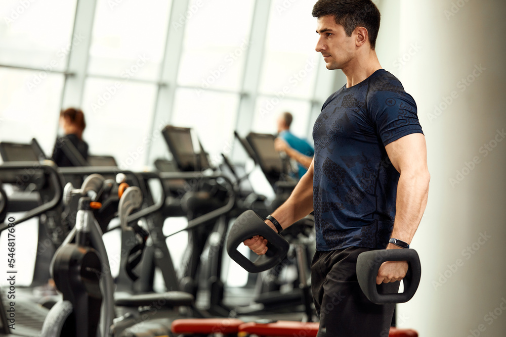 Handsome Athletic Men Exercising With Kettlebell in the gym Handsome Athletic Men Exercising With Kettlebell in the gym