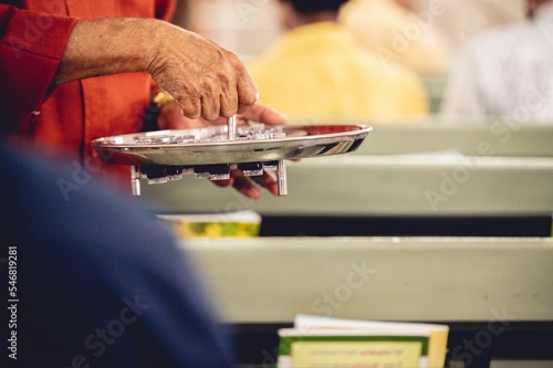 Fototapeta Person treats the red wine with small glasses to churchgoers to observe communio