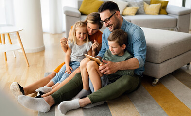 Happy young family having fun time at home. Parents with children using tablet