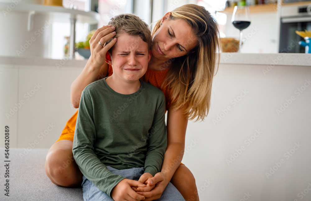 Portrait of mother consoling her crying sad injured son. Child family