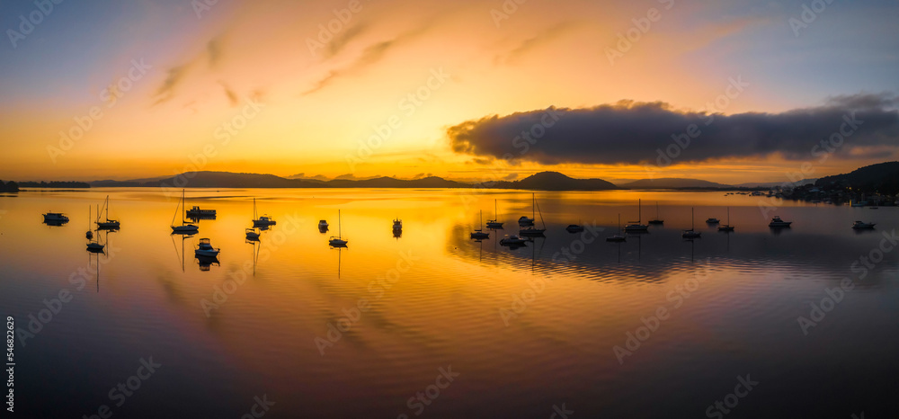 Sunrise over the water with fog, boats, clouds and reflections