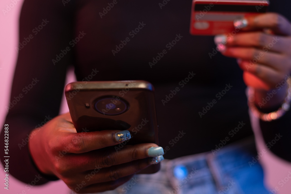 black woman using her phone and credit card black woman using her phone and credit card