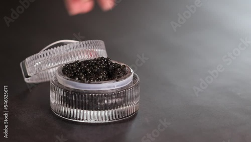 I remove the lid from the container with black caviar, and take black caviar with a spoon.