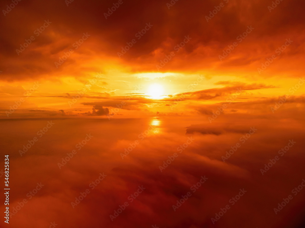 A red burning sunset over the sea and clouds The drone flies over foggy and fluffy clouds. Abstract aerial nature summer ocean sunset sea and sky background. Vacation, travel and holiday concept