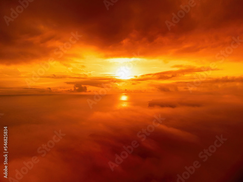 A red burning sunset over the sea and clouds The drone flies over foggy and fluffy clouds. Abstract aerial nature summer ocean sunset sea and sky background. Vacation  travel and holiday concept