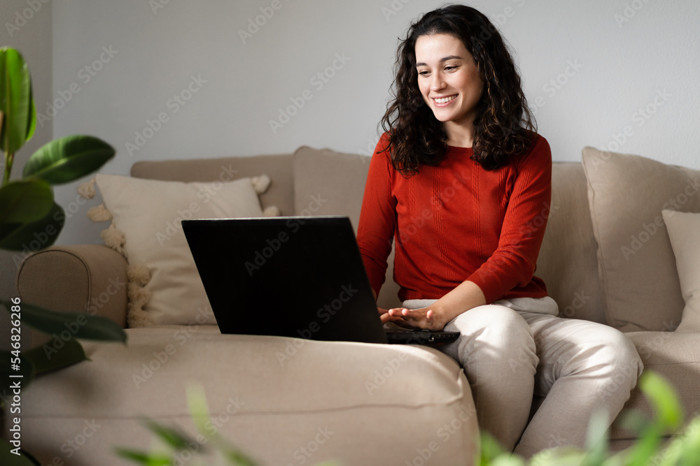 Happy young woman typing in the laptop sitting on the couch Happy young woman typing in the laptop sitting on the couch