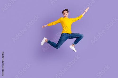 Full size photo of crazy carefree guy jump high hands aside isolated bright studio shot background