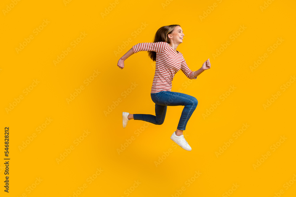 Full side view of smiling cheerful young brunette woman jumping like running isolated on bright color background