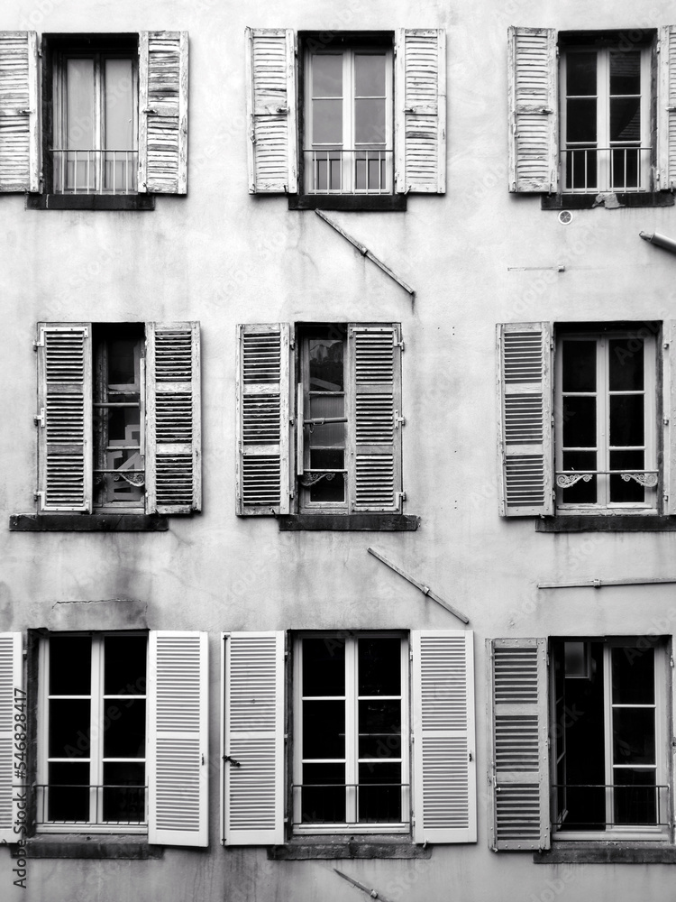 Obraz premium fenêtres d'une facade d'un vieil immeuble en France, photo en noir et blanc
