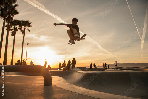 Teenage boy skating at skatepark during sunset photo