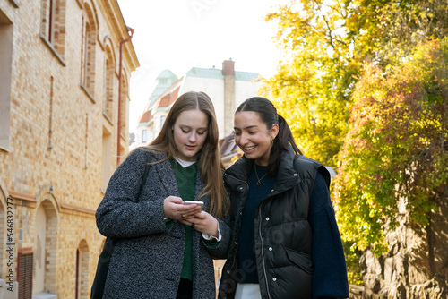 Young women using smart phone on city street