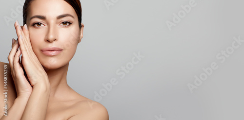 Beauty and Skincare Concept. Beautiful natural young woman face with nude makeup on a flawless skin on a panorama banner with lateral grey copyspace