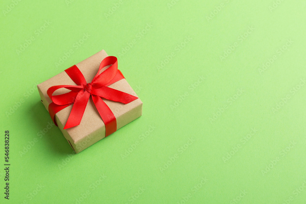 Wrapped christmas or other holiday handmade present in craft paper with colored ribbon. Present box, decoration of gift on table, top view with copy space