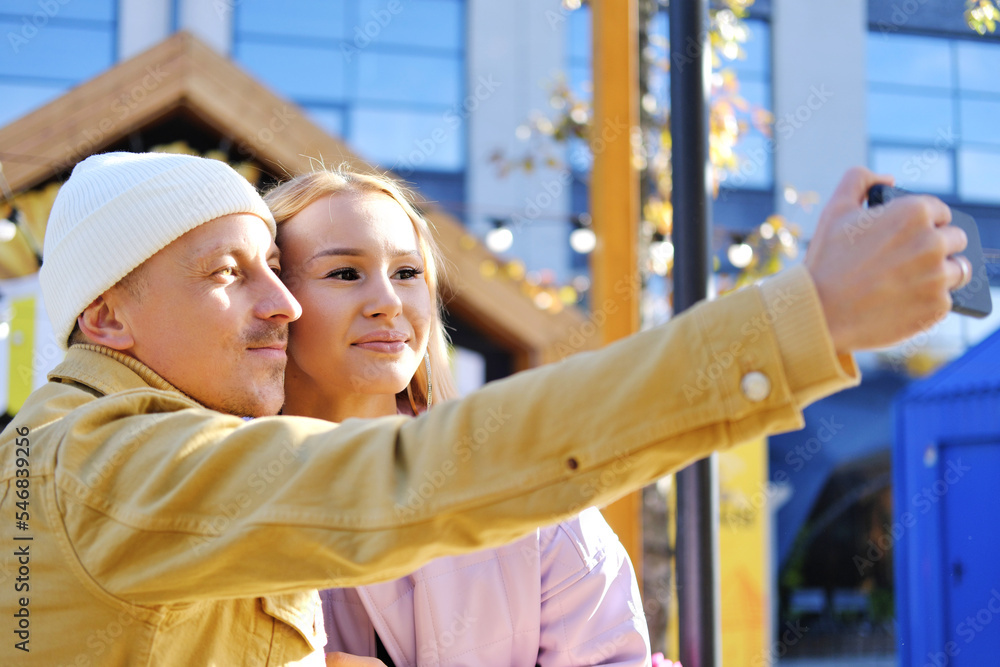Obraz premium A couple in love, a guy and a girl, take a selfie together in sunny weather. couple looking at camera and smiling