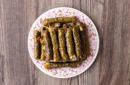 Delicious dolma (sarma) stuffed grape leaves rice, white yogurt sauce. Lebanese dolma sarma on plate. Lebanon turkish greek middle eastern cuisine. (Turkish name; Yaprak sarma)