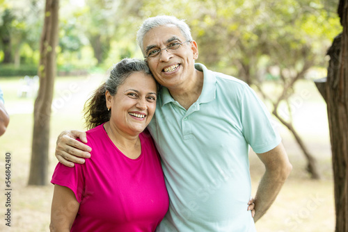 Portrait of Happy indian senior couple at summer park. Old Asian man and woman standing outdoor smiling. retirement life,