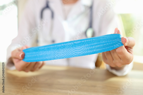 Physical therapist with medical tape in hands sitting at desk in clinic.