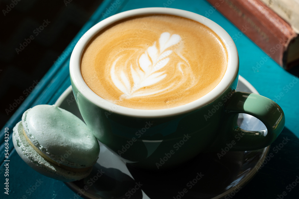 Cappuccino with blue macaron on the blue green table Cappuccino with blue macaron on the blue green table