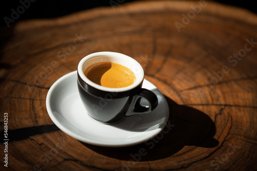 Espresso with thick crema in a black cup on a wooden table
