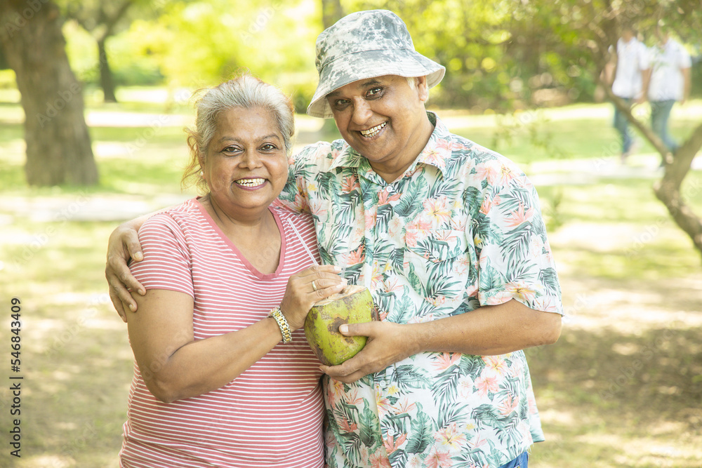 © GAJENDRRA BHATI  - Happy indian senior couple having coconut water at summer park. Old people enjoying retirement life.