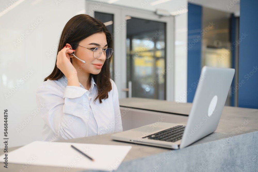 friendly young woman behind the reception desk administrator friendly young woman behind the reception desk administrator