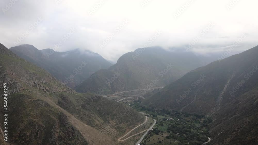 Circling misty drone shot of a road in between green and rocky mountains in the highlands of Peru Circling misty drone shot of a road in between green and rocky mountains in the highlands of Peru