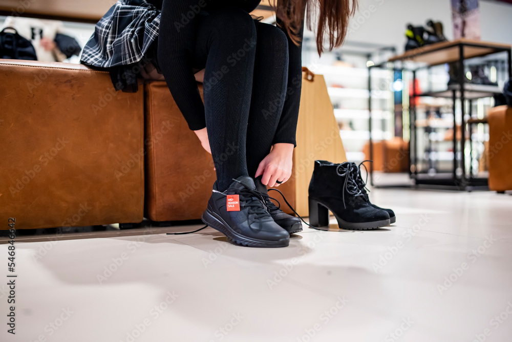 Fototapeta premium Woman trying new black shoes sitting in a shop