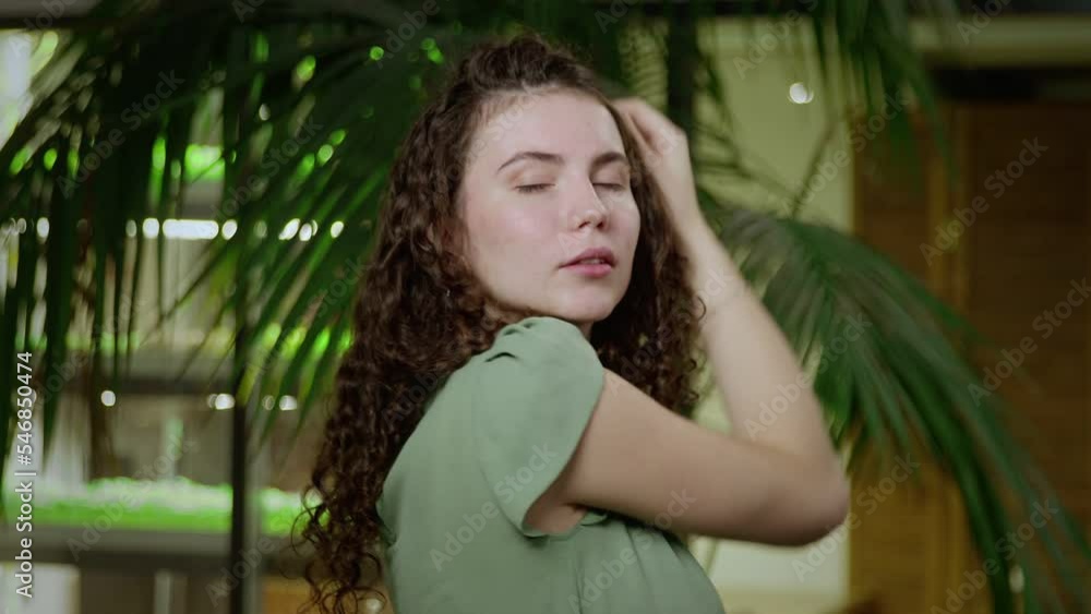 Close-up of a young woman with brown curly hair posing for the camera. Portrait of a girl Close-up of a young woman with brown curly hair posing for the camera. Portrait of a girl