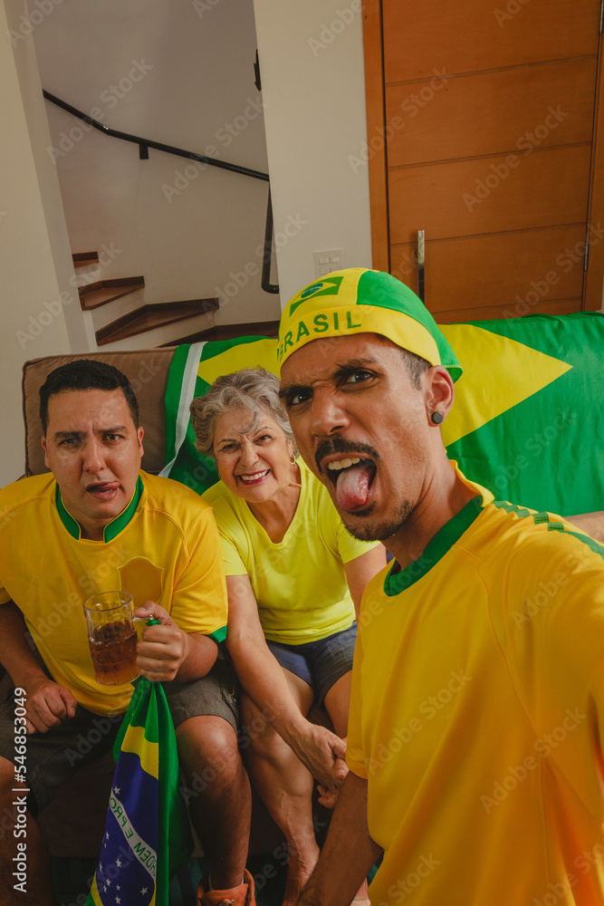 Brazilian Mixed Race Family Celebrating the cup in the living room watching football game. Family taking selfie photo while watching cup game. Brazilian Mixed Race Family Celebrating the cup in the living room watching football game. Family taking selfie photo while watching cup game.