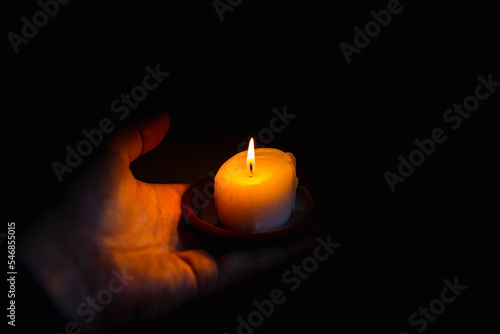 Burning candle in a mans hand at dark background.A man of prayer is praying, holding one burning candle.Religion concept.