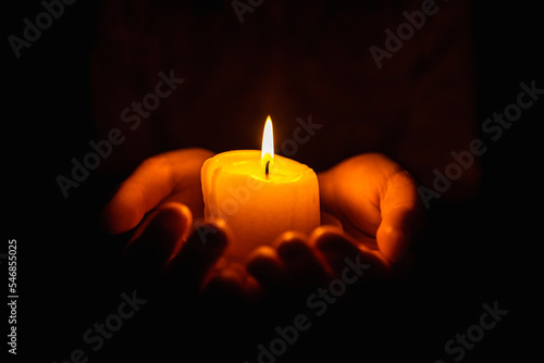 Burning candles in the boy hands on a dark background.Religious concept.