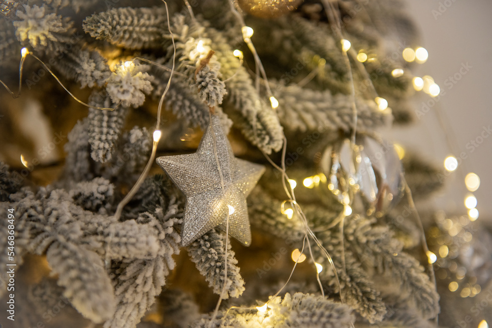 Toys, garlands, balls with feathers, deer hang on artificial, snow-covered Christmas tree. Toys, garlands, balls with feathers, deer hang on artificial, snow-covered Christmas tree.