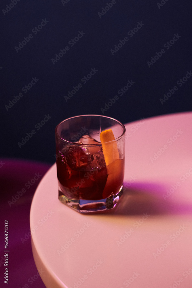 cocktail with alcohol and whiskey and ice and fresh orange peel in a rocks glass, on a white table cocktail with alcohol and whiskey and ice and fresh orange peel in a rocks glass, on a white table