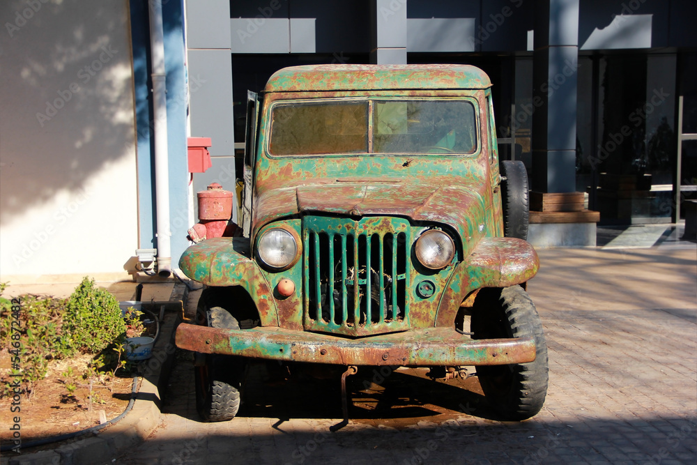An old green truck with a body and rust spots