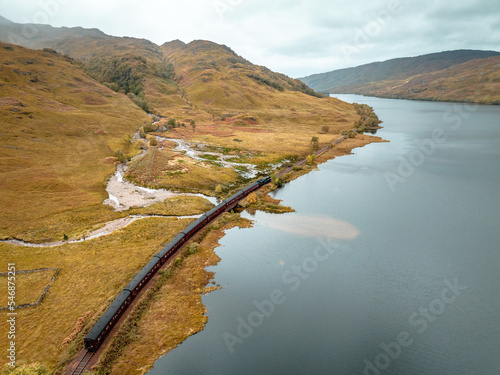 Steam Train in Scotland Passing by a Loch in the Highlands photo
