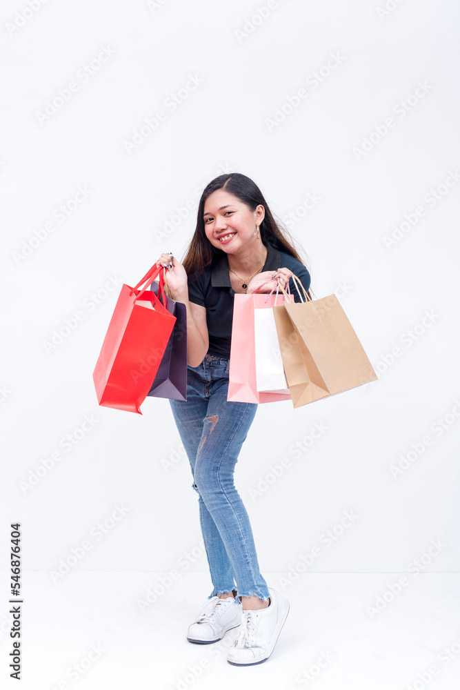 An elated asian woman holding shopping bags on both hands after going on a shopping spree. Isolated on a white background. Retail and sale concepts. An elated asian woman holding shopping bags on both hands after going on a shopping spree. Isolated on a white background. Retail and sale concepts.