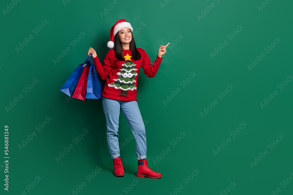 Full length photo of cute funny girl dressed ugly print red x-mas pullover rising bargains pointing empty space isolated green color background