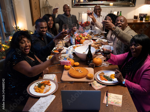 Family having video call and raising toast during Thanksgiving dinner