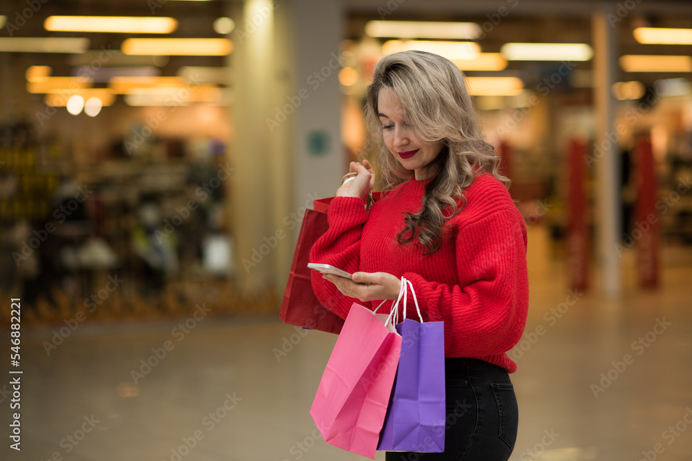 A woman shopping with a smartphone in a shopping mall, a happy girl talking on the phone in a shopping mall, holding shopping bags in her hands A woman shopping with a smartphone in a shopping mall, a happy girl talking on the phone in a shopping mall, holding shopping bags in her hands