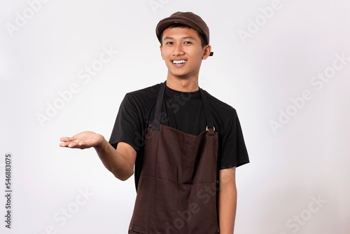 Handsome barista asian man wearing brown apron and black t-shirt isolated over white background pointing with fingers. showing product recommendation advertising concept